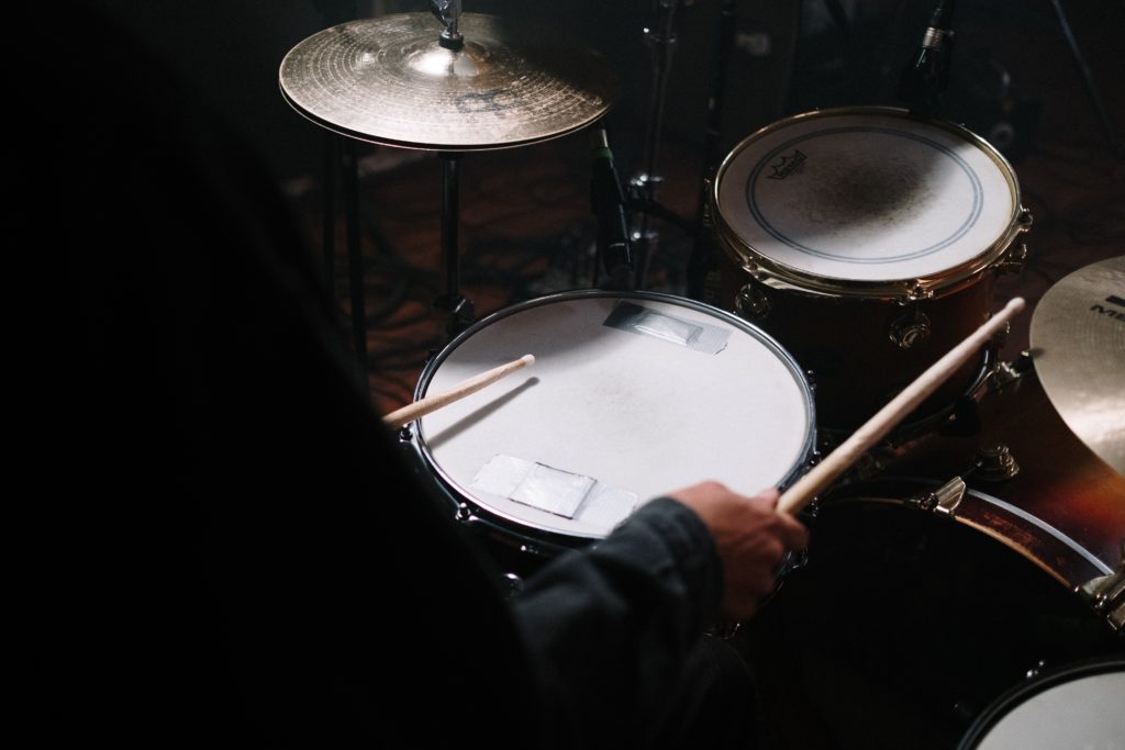 Shoulder shot of someone playing a drum kit. Hi hat, high tom and snare with nylon tip sticks